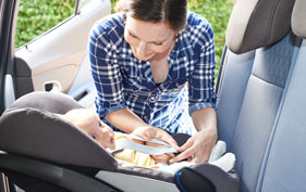 Mother putting baby in car seat