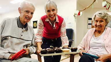 Interim care Recreational Officer Mary shares birthday cupcakes with patients Allan and Dorothy.